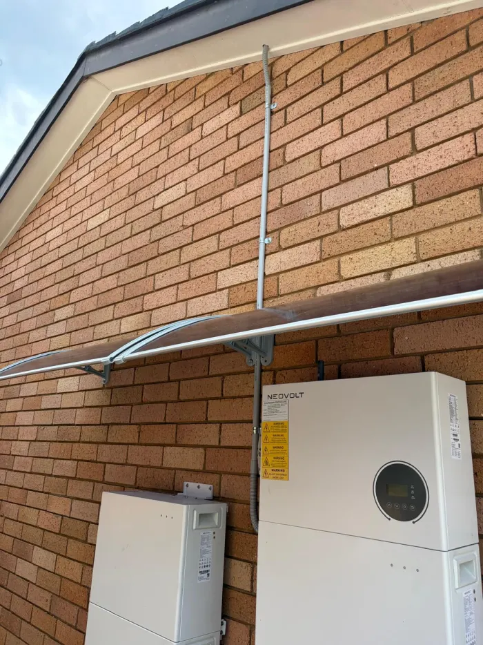 NeoVolt battery equipment installed on an exterior brick wall