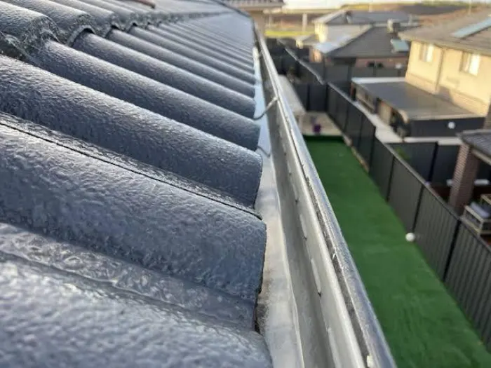 Gutter running clear along a tile roof after being cleaned and flushed